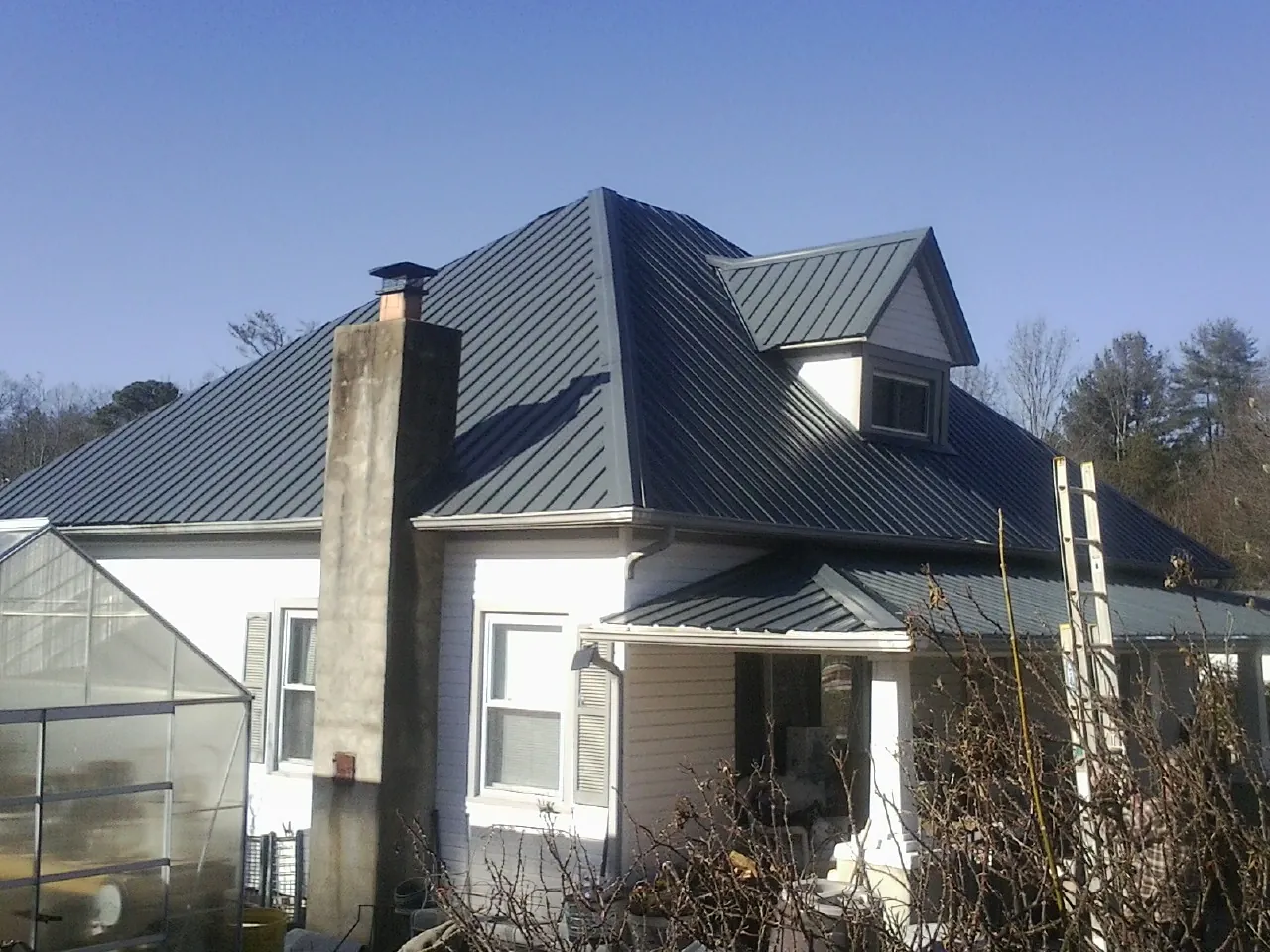 Dark blue standing seam metal roof on a white farmhouse with dormer — Slate & Tile Roof Repair by Roofing Brothers in Gansevoort