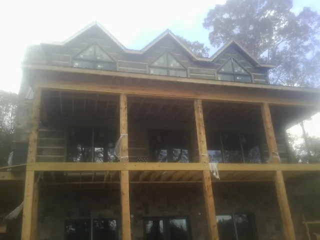 Dormers and porch framing on a large log home under construction — Roof Coating work by our crew in Gansevoort