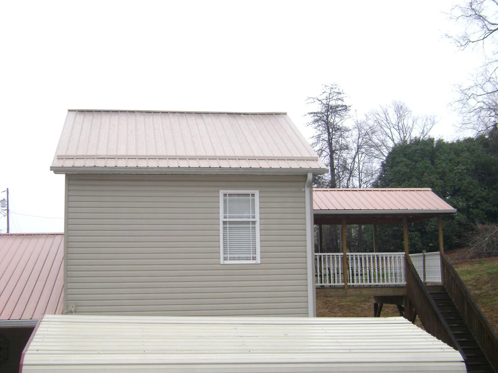 Tan metal roofs on a two story addition and attached porch, from a Roof Replacement job in Gansevoort