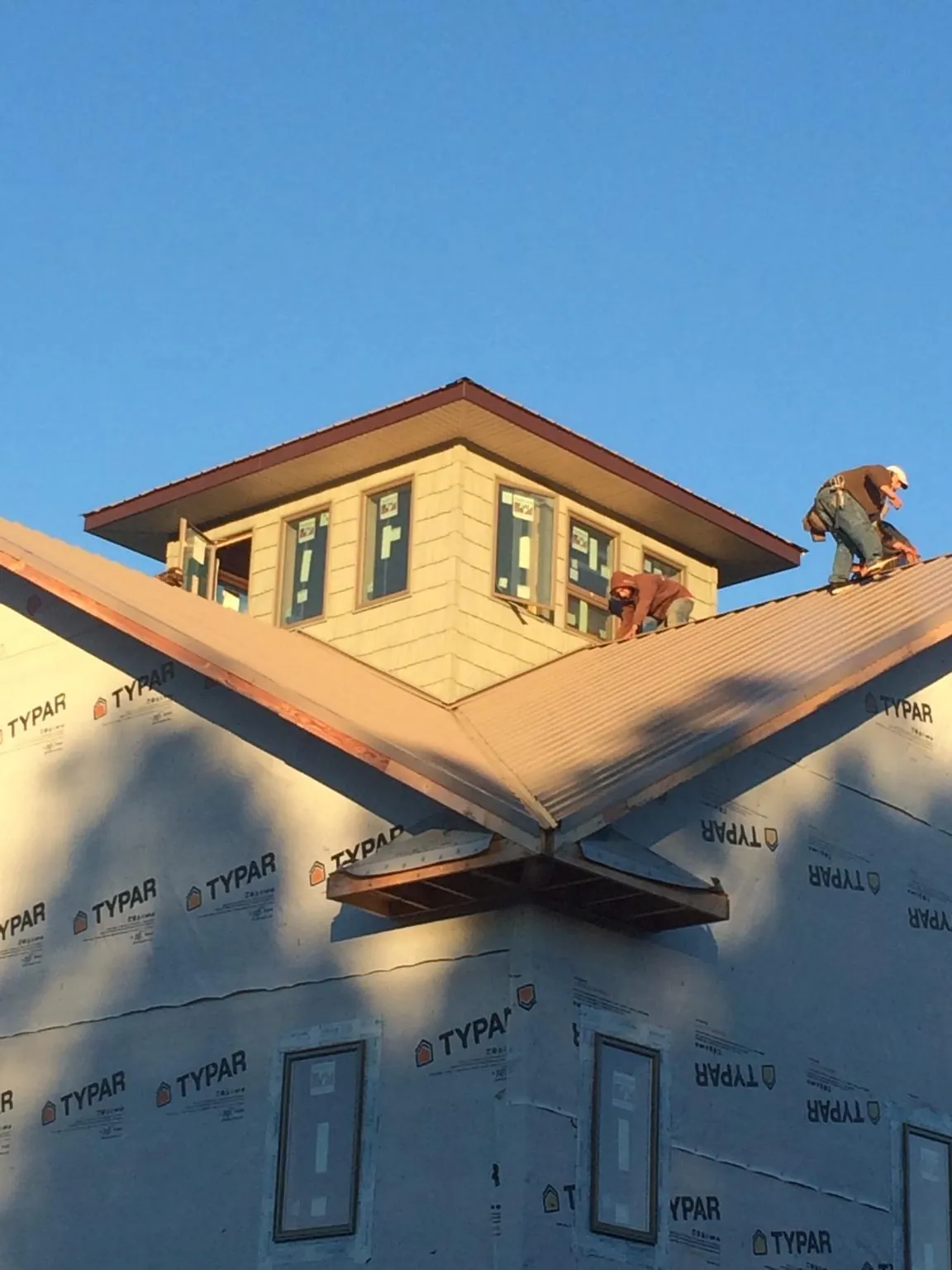Roofers working around a rooftop cupola on a new metal roof at sunset — Roof Waterproofing in Gansevoort by Roofing Brothers